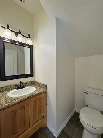 a bathroom with a granite countertop sink toilet and mirror
