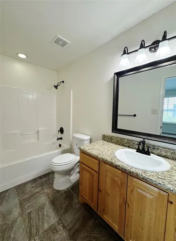 a bathroom with a granite countertop sink toilet mirror and bathtub