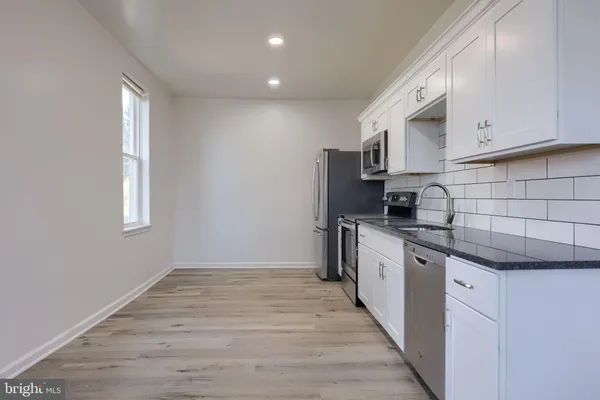 a view of kitchen with stainless steel appliances a refrigerator and white cabinets