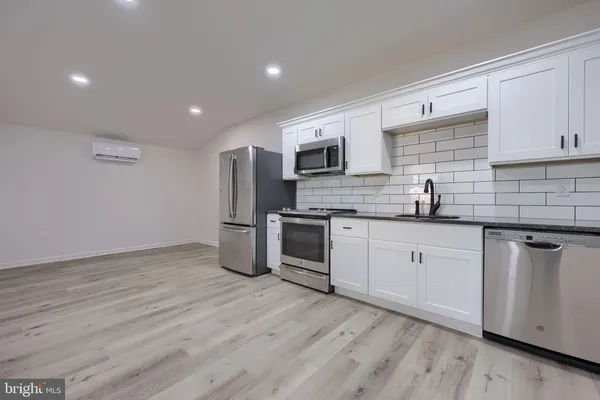 a kitchen with stainless steel appliances granite countertop a stove a sink dishwasher a microwave oven and a refrigerator with wooden floor