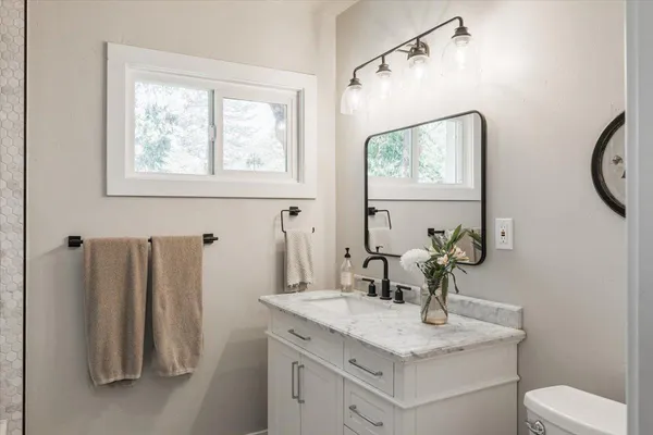 a bathroom with a granite countertop sink a toilet and a mirror