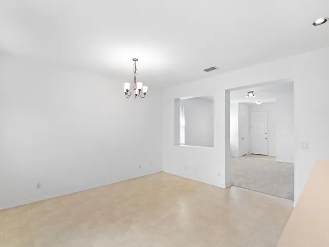 an empty room with chandelier fan and windows
