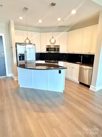 a kitchen with stainless steel appliances a sink a stove a microwave a sink a refrigerator and white cabinets