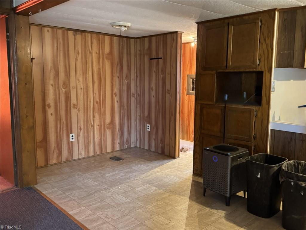 2023 Benaja Road Reidsville, NC 27320 - Photo 11 of 36 Dining Area and Built-In Cabinets at 2023 Benaja Road, Reidsville, NC 27320, Rockingham County. Dining area with tile flooring and wood paneling walls. Built-in wood cabinets with upper and lower storage. Transition from carpeted living area,
