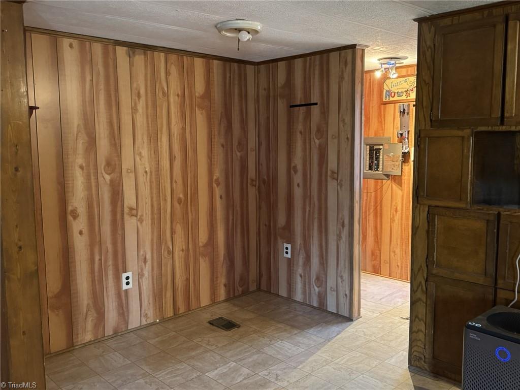 2023 Benaja Road Reidsville, NC 27320 - Photo 12 of 36 Dining Area with Laundry Access and Electrical Panel at 2023 Benaja Road, Reidsville, NC 27320, Rockingham County. Second view of the dining area showing wood paneling, electrical panel, and laundry area access. Built-in cabinets on the right.