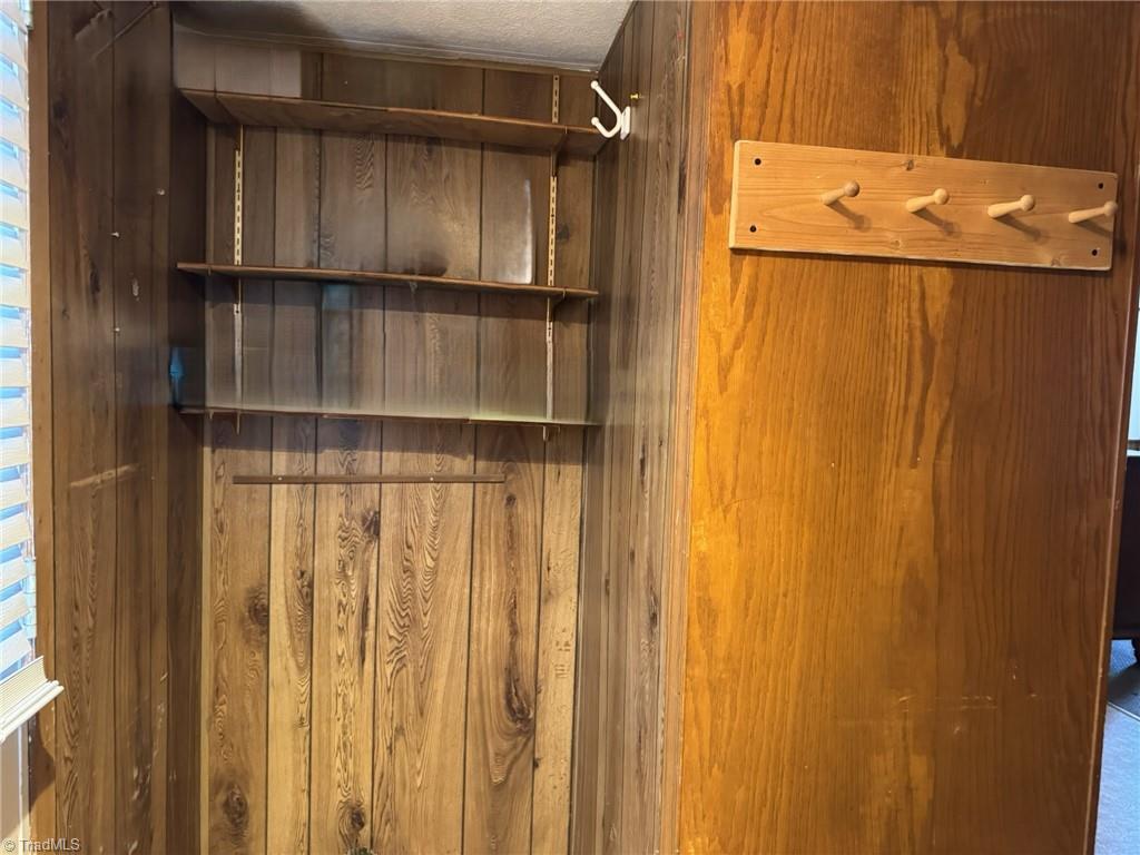 2023 Benaja Road Reidsville, NC 27320 - Photo 23 of 36 Closet with Built-In Wood Shelves and Coat Hooks at 2023 Benaja Road, Reidsville, NC 27320, Rockingham County. Closet area with built-in wood shelving and adjustable shelf brackets. Wall-mounted coat hook rack. Wood paneling interior. Functional storage space.