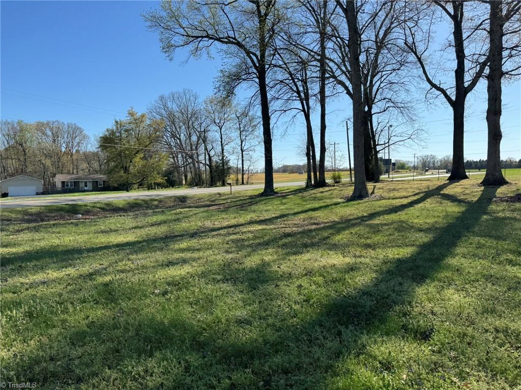 2023 Benaja Road Reidsville, NC 27320 - Photo 4 of 36 Front Yard Road View Showing Large Lot at 2023 Benaja Road, Reidsville, NC 27320, Rockingham County. View from the front yard looking toward the road. Spacious lot with green lawn and rural surroundings. Neighboring home and open farmland visible across the road.