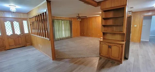 an empty room with a window and chandelier fan