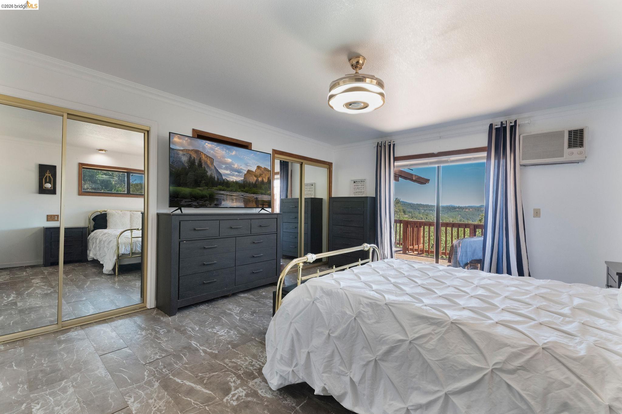 22963 Robertson Ranch Road Sonora, CA 95370 - Photo 23 of 90 Sliding glass doors opening to an exterior deck, mirrored closet doors, tile flooring, and a ceiling-mounted light fixture