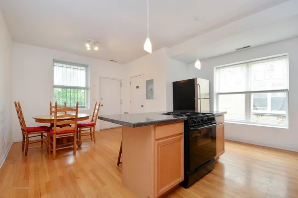 a kitchen with stainless steel appliances granite countertop a stove top oven a sink dishwasher a dining table and chairs with wooden floor