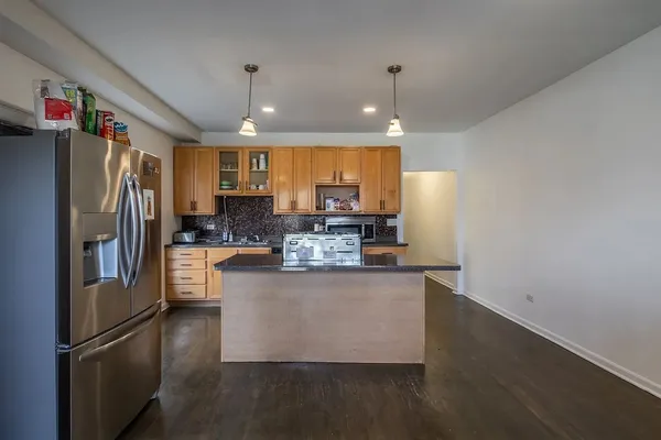 a kitchen with stainless steel appliances granite countertop a refrigerator a sink dishwasher a stove and a refrigerator with wooden floor