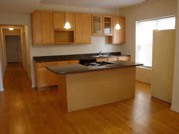 a kitchen with stainless steel appliances granite countertop a sink a stove a refrigerator a microwave oven with wooden floor and cabinets