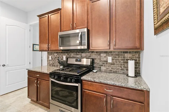 a kitchen with granite countertop a sink a counter top space and stainless steel appliances