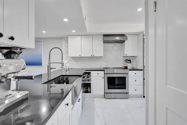 a kitchen with stainless steel appliances kitchen island granite countertop a dining table chairs and a refrigerator