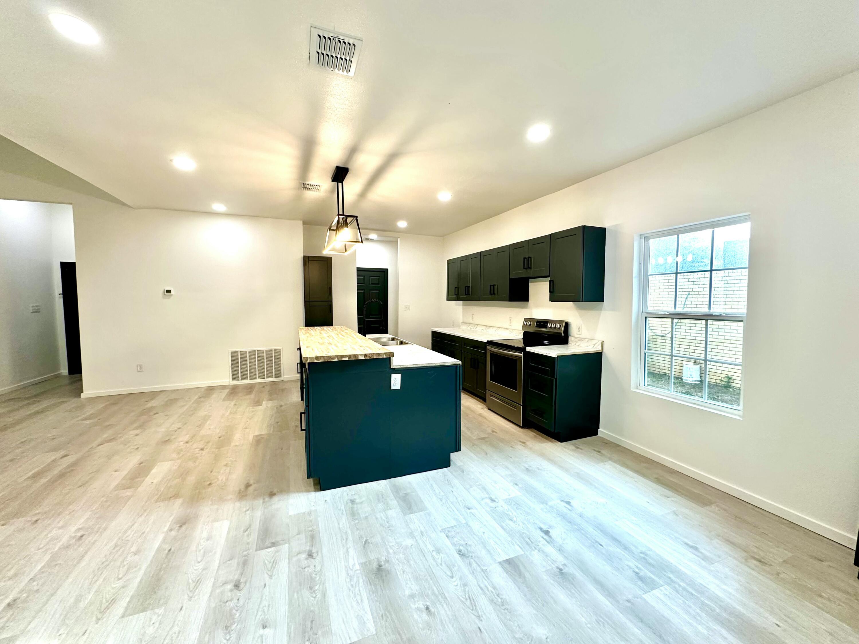 2617 47th Street Lubbock, TX 79413 - Photo 5 of 12 a large kitchen with stainless steel appliances kitchen island granite countertop a refrigerator and a stove top oven