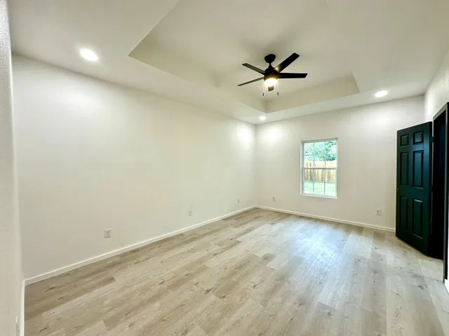 an empty room with a window and ceiling fan