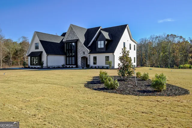 a front view of house with yard and trees in the background