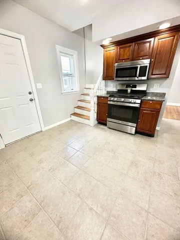 a view of kitchen with stainless steel appliances wooden floor and window