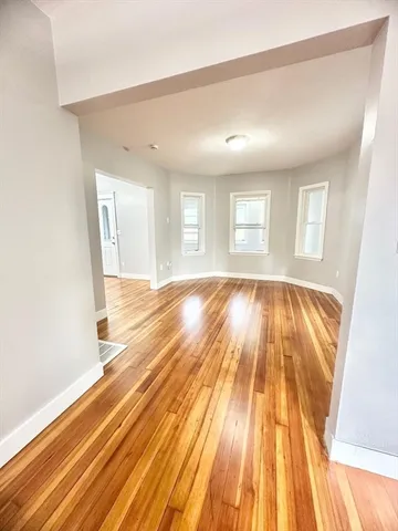 a view of an empty room with wooden floor and chandelier