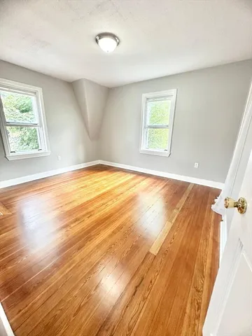 a view of empty room with window and wooden floor