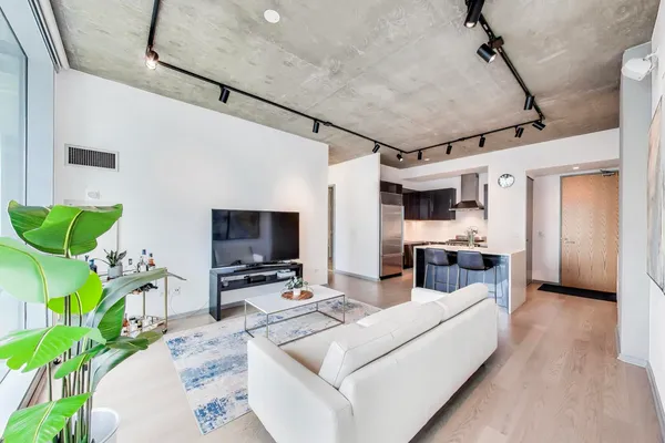 a living room with furniture kitchen view and a wooden floor