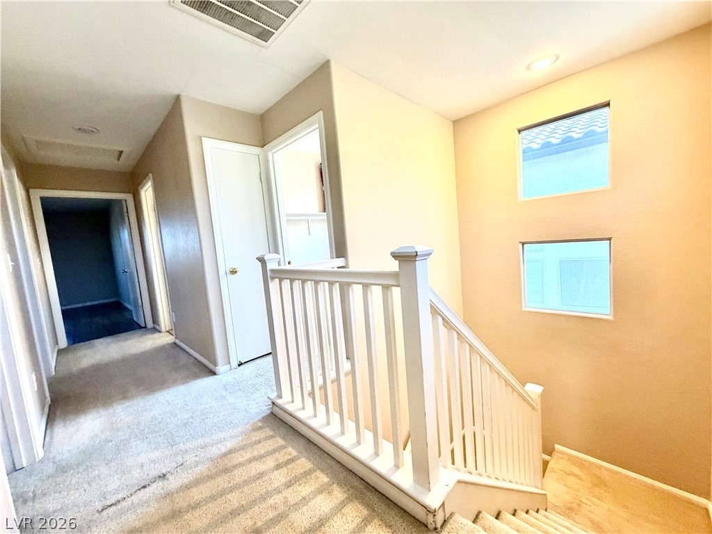 3936 Gold Point Street Las Vegas, NV 89129 - Photo 17 of 23 Natural light filters into this carpeted hallway, revealing a classic white banister and recessed lighting.