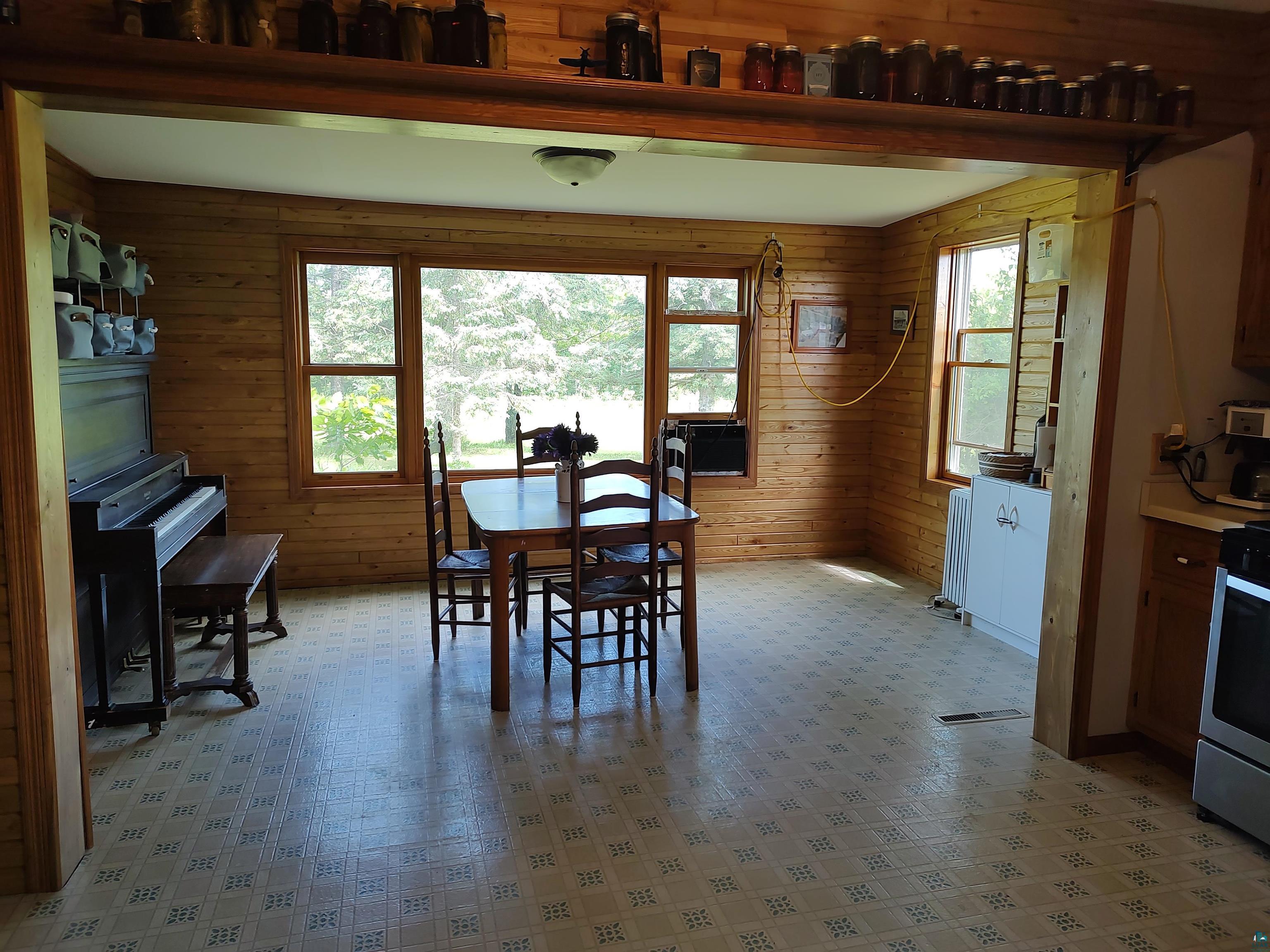 2585 Hautala Road Iron River, WI 54847 - Photo 4 of 28 Spacious dining area featuring wood-paneled walls, multiple windows, and patterned floor tiling