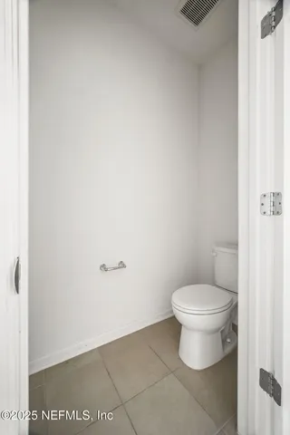 a white toilet sitting next to a white wall