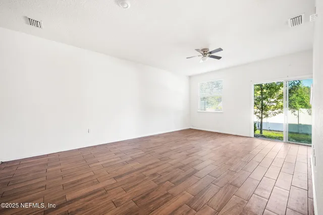 an empty room with windows and ceiling fan