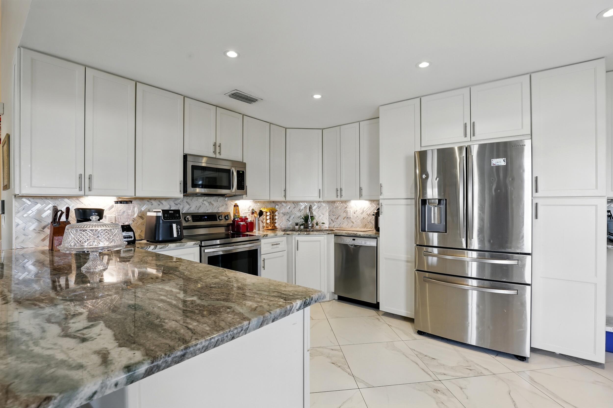 a kitchen with granite countertop a refrigerator sink and microwave
