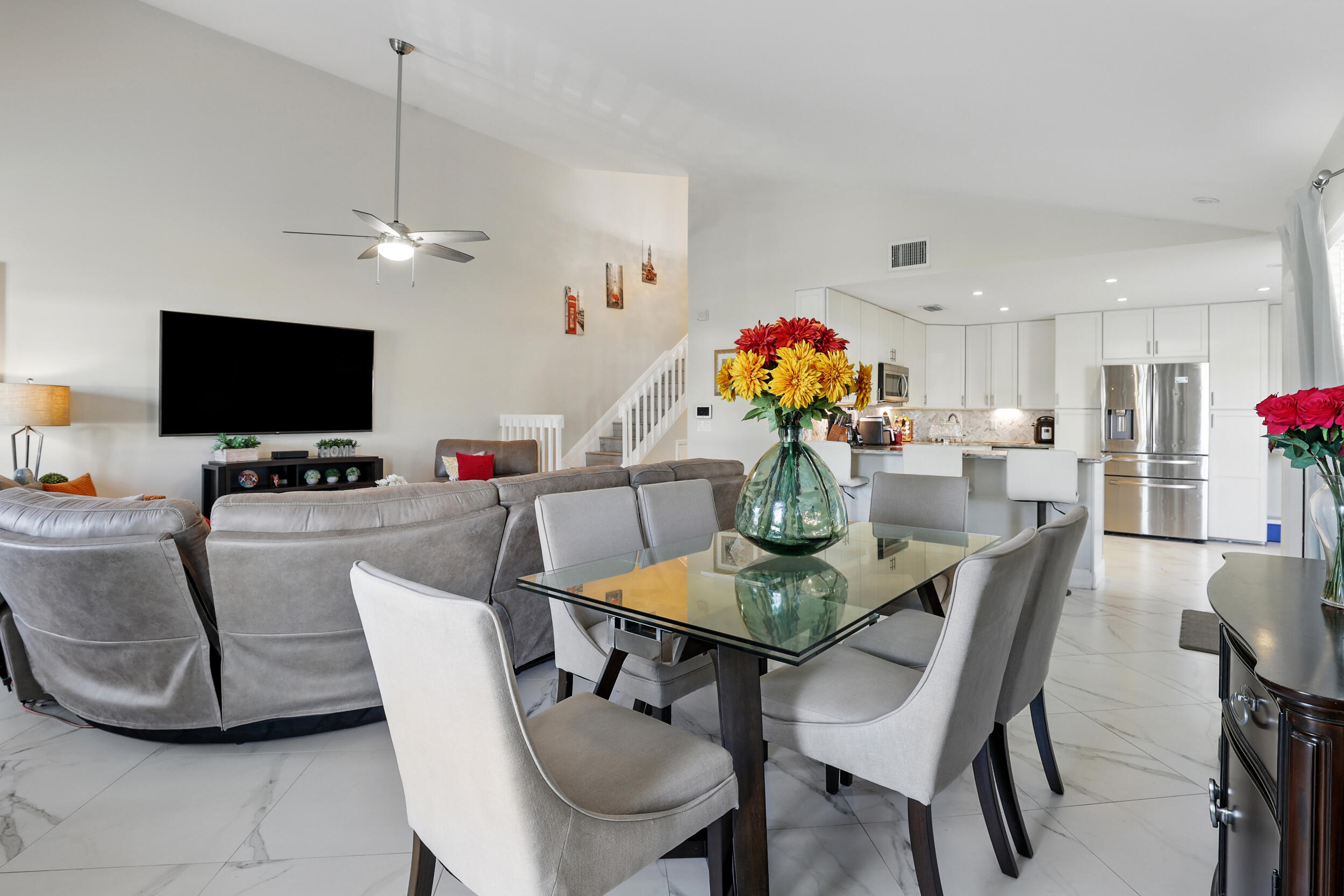 4491 Willow Pond Road, Unit B West Palm Beach, FL 33417 - Photo 11 of 29 a dining room with furniture a chandelier and a flat screen tv