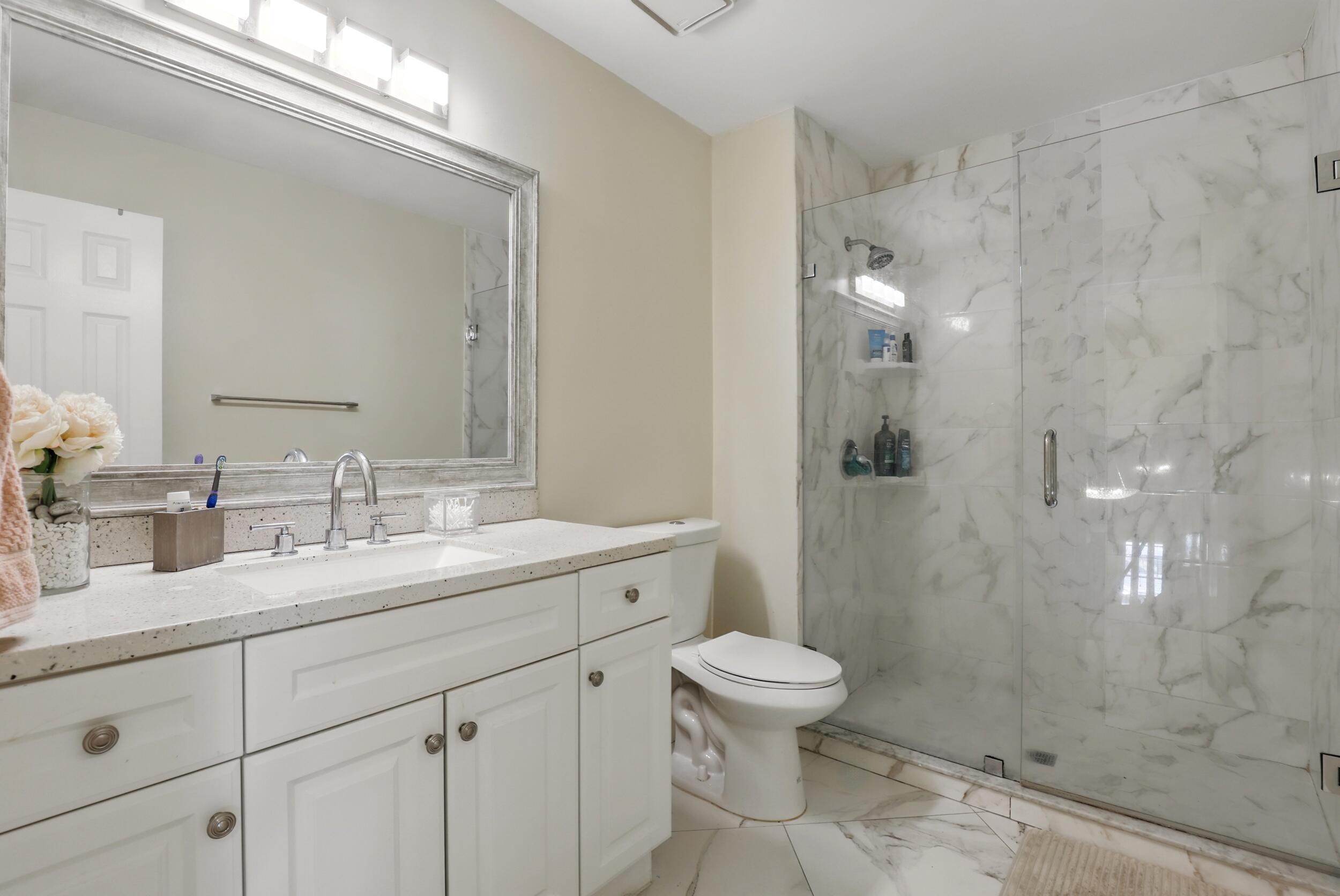 4491 Willow Pond Road, Unit B West Palm Beach, FL 33417 - Photo 18 of 29 a bathroom with a shower sink vanity mirror and toilet