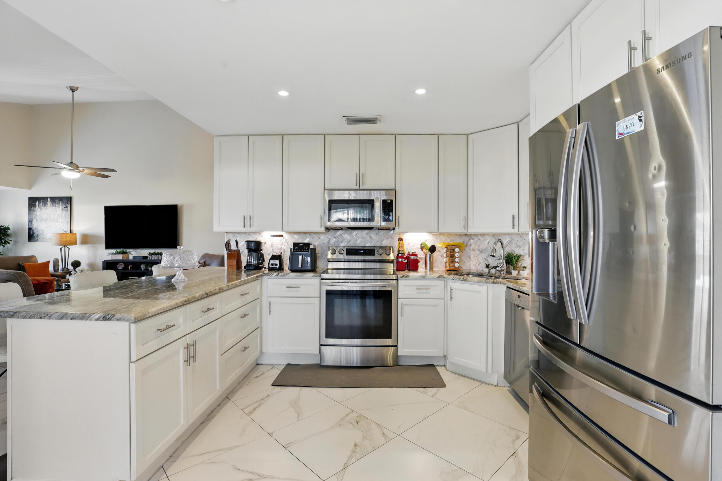 4491 Willow Pond Road, Unit B West Palm Beach, FL 33417 - Photo 2 of 29 a kitchen with white cabinets and stainless steel appliances