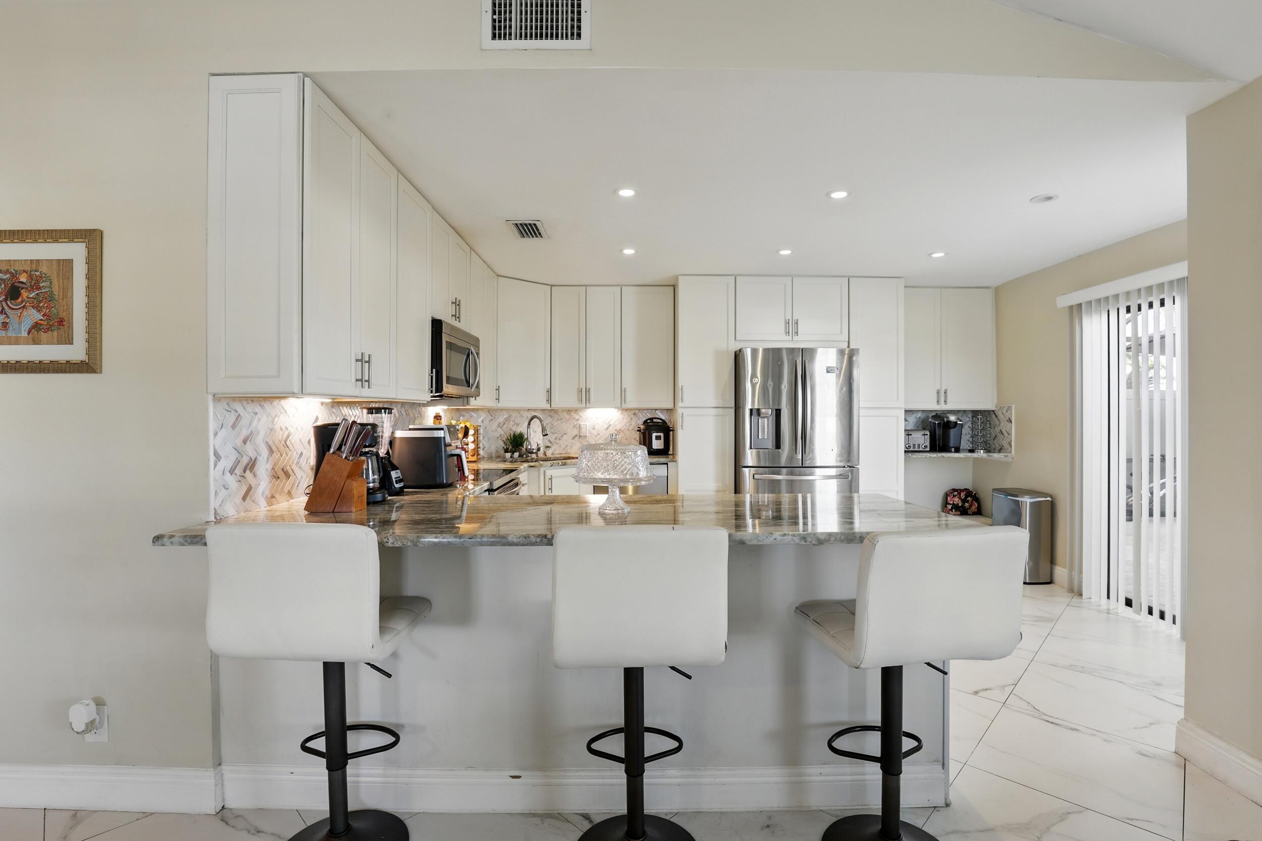 4491 Willow Pond Road, Unit B West Palm Beach, FL 33417 - Photo 6 of 29 a kitchen with stainless steel appliances granite countertop a refrigerator and a stove top oven
