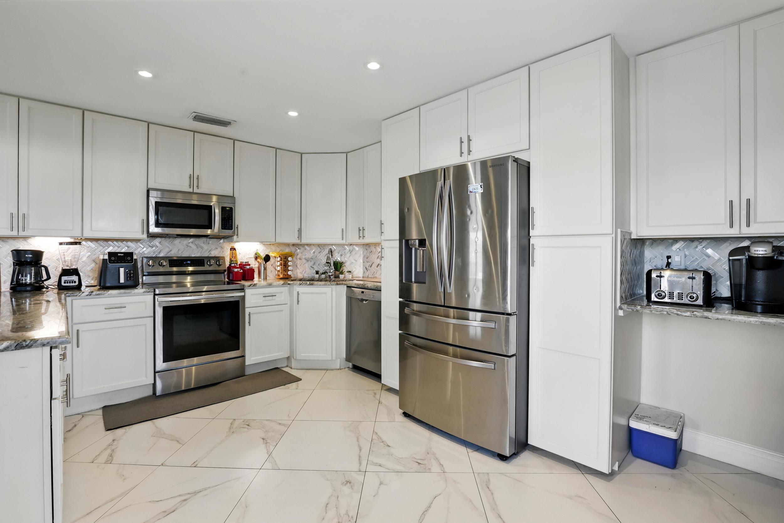 4491 Willow Pond Road, Unit B West Palm Beach, FL 33417 - Photo 9 of 29 a kitchen with granite countertop a refrigerator and a stove top oven