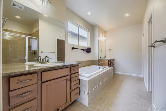 a bathroom with a double vanity sink a mirror and a bathtub