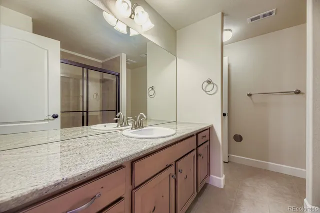 a bathroom with a granite countertop sink a mirror and a shower