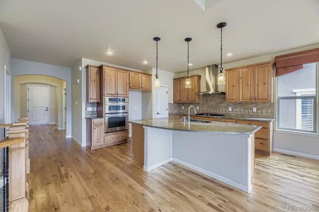 a large kitchen with kitchen island a large counter top stainless steel appliances and cabinets