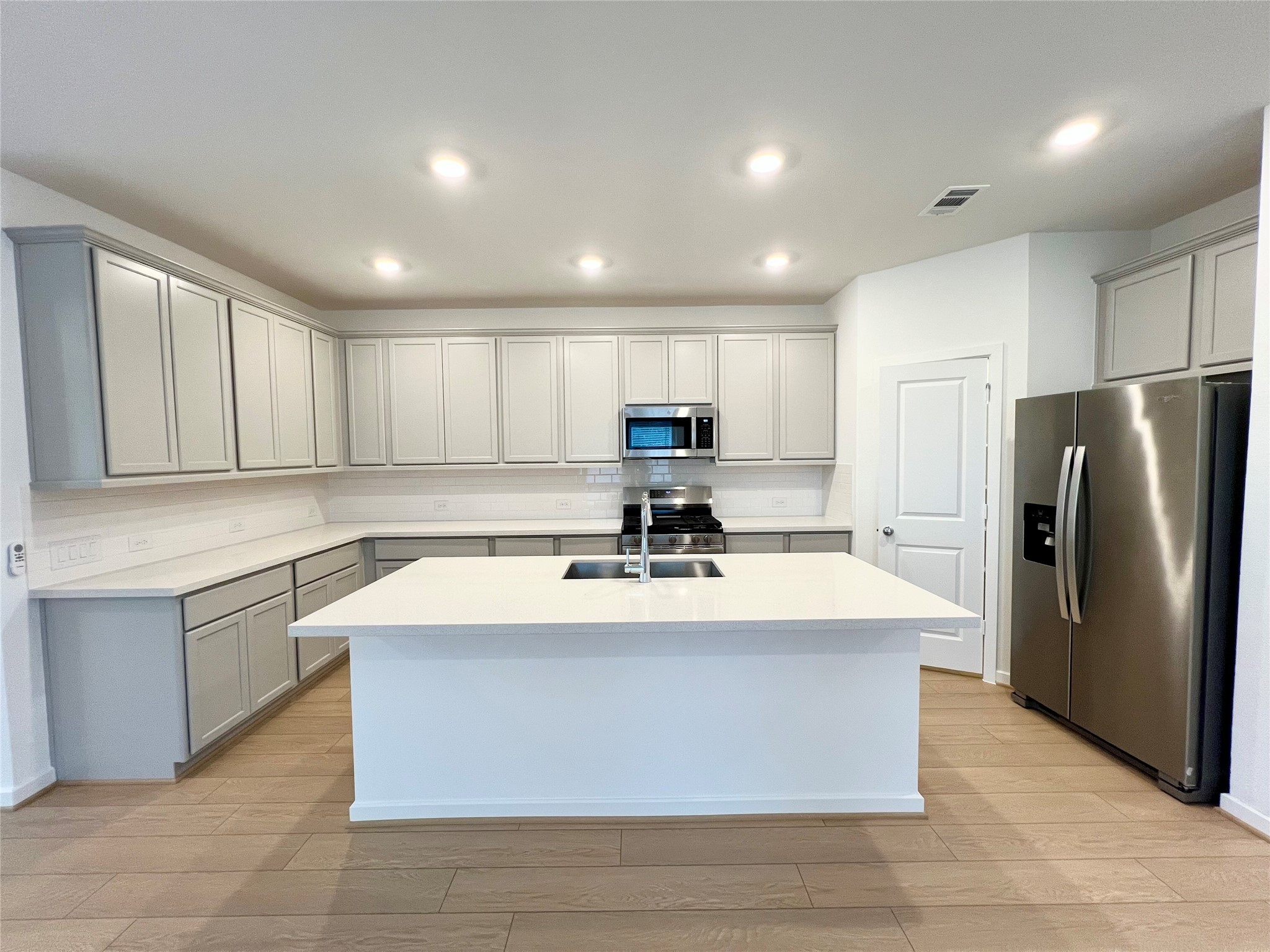 a large kitchen with kitchen island a sink a stove a refrigerator and a cabinets