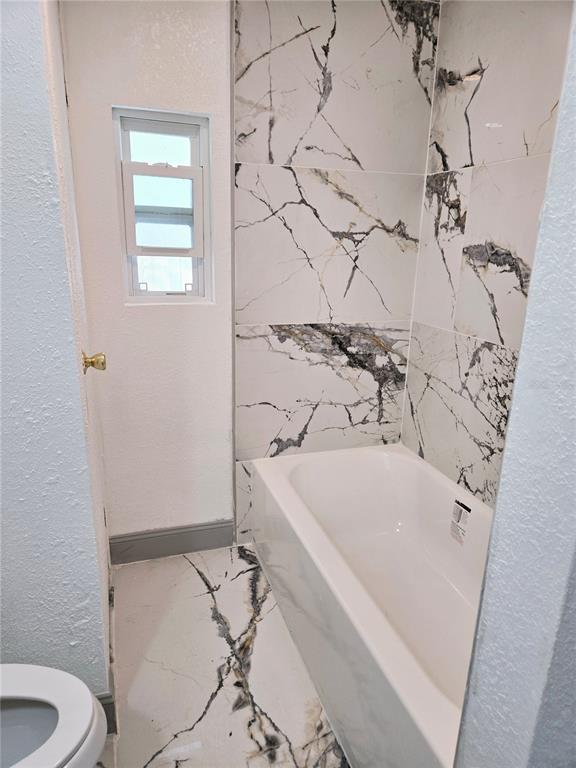 5860 Southwest 64th St Road Ocala, FL 34474 - Photo 7 of 11 a bath tub sitting next to a white toilet and a shower