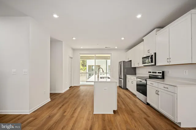 a open kitchen with granite countertop a stove top oven a sink dishwasher a refrigerator and cabinets with wooden floor