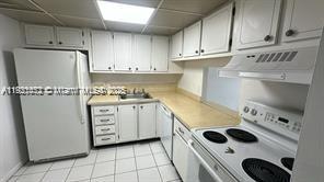 500 Executive Center Drive, Unit 1C West Palm Beach, FL 33401 - Photo 1 of 12 a kitchen with white cabinets and stove
