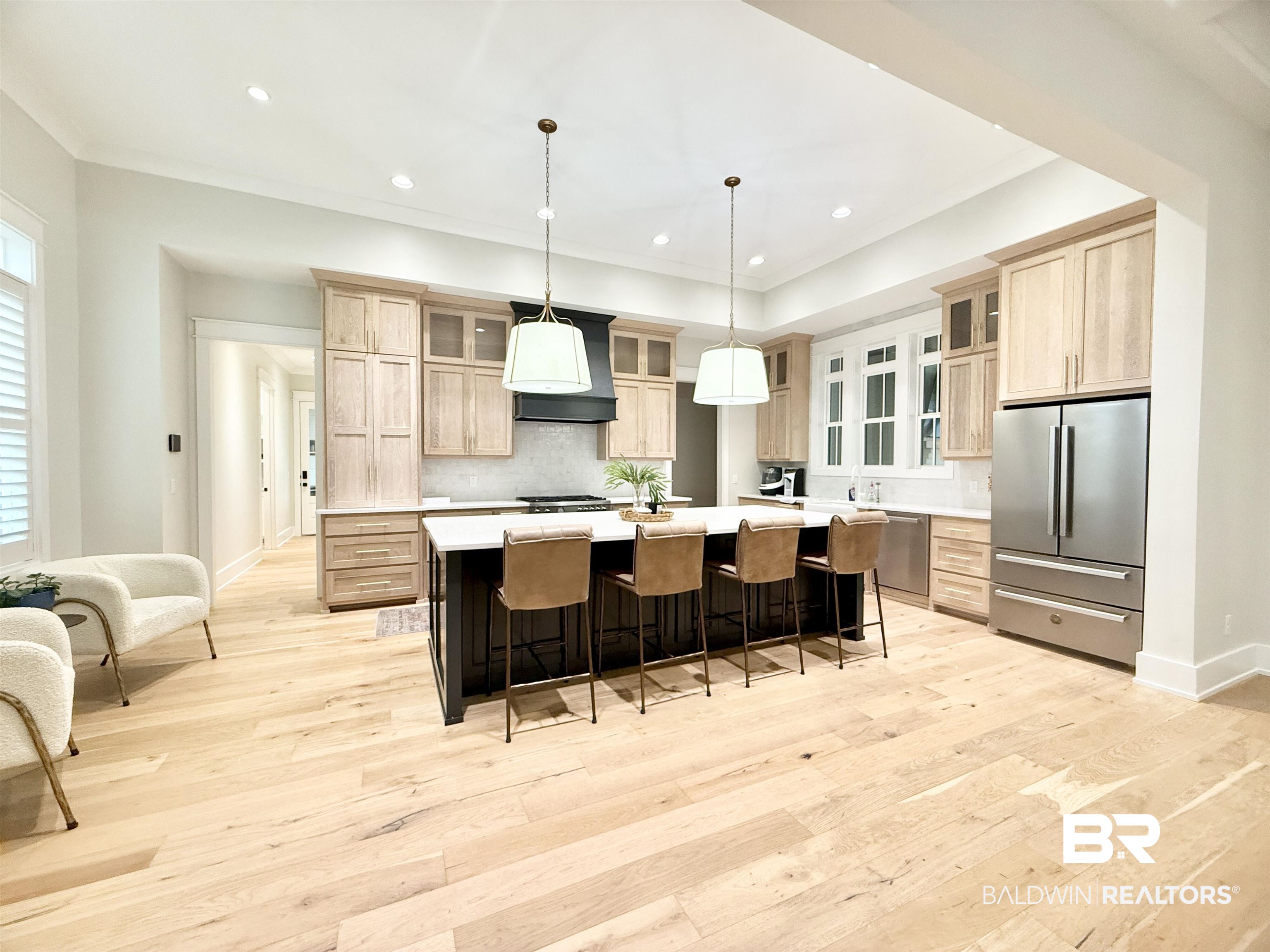 21767 Gallery Boulevard Fairhope, AL 36532 - Photo 11 of 74 Kitchen featuring stainless steel appliances, light countertops, light brown cabinetry, light wood finished floors, and a large island