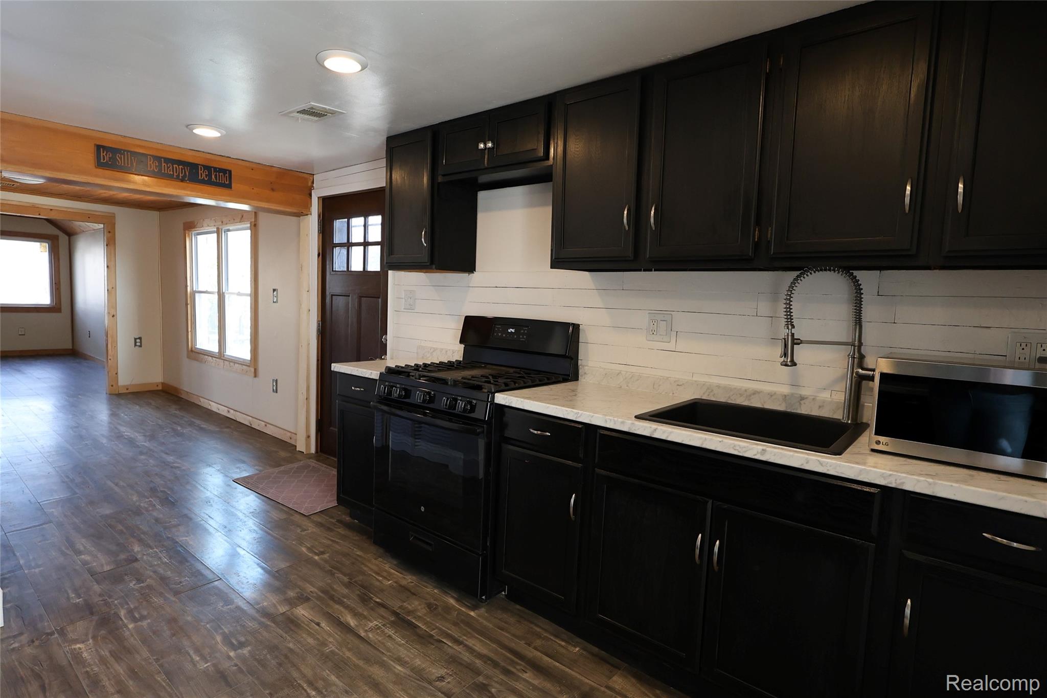15676 Frazho Road Roseville, MI 48066 - Photo 7 of 20 Kitchen featuring dark cabinetry with brushed nickel hardware, white stone-finish countertops, and a white plank-style backsplash