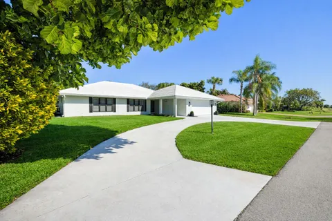 a view of a white house with a yard and potted plants
