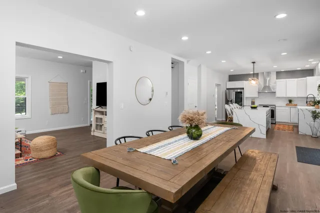 a living room with stainless steel appliances furniture dining table and wooden floor