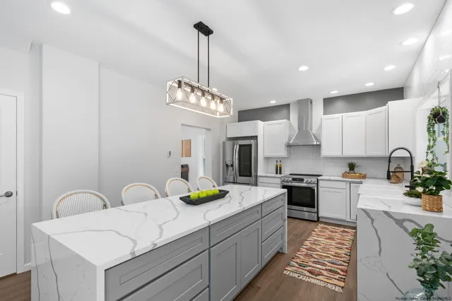 a kitchen with stainless steel appliances a sink dishwasher a stove a dining table and chairs with wooden floor