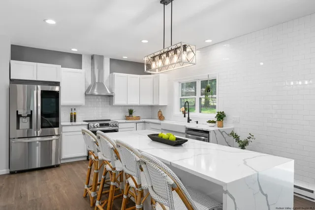 a kitchen with a stove a chandelier and white cabinets