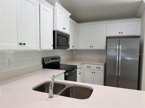 a kitchen with granite countertop white cabinets sink and stainless steel appliances