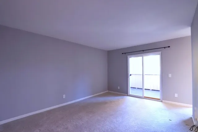 a view of an empty room with closet and a window